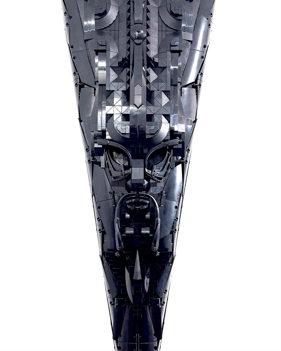 This sculpture by Toronto-based artist Ekow Nimako is part of a series of artworks entitled Building Black Amorphia: Spiritual Starships. The series is inspired by West African mask-making practices, Afrofuturism, interstellar vessels, and various hybridized forms. Each mask draws inspiration from familiar or unfamiliar science fiction spacecrafts, establishing links between the sci-fi genre and the various world cultures from which much of its lore is appropriated. EBO’ZHE deftly harnesses the vehicular and aerodynamic form of the isosceles triangle, while simultaneously upholding a traditional mask aesthetic which features an elongated face with an austere expression. EBO&#39;ZHE is physically located in the Seneca @ York Library. Photo by Ekow Nimako. 